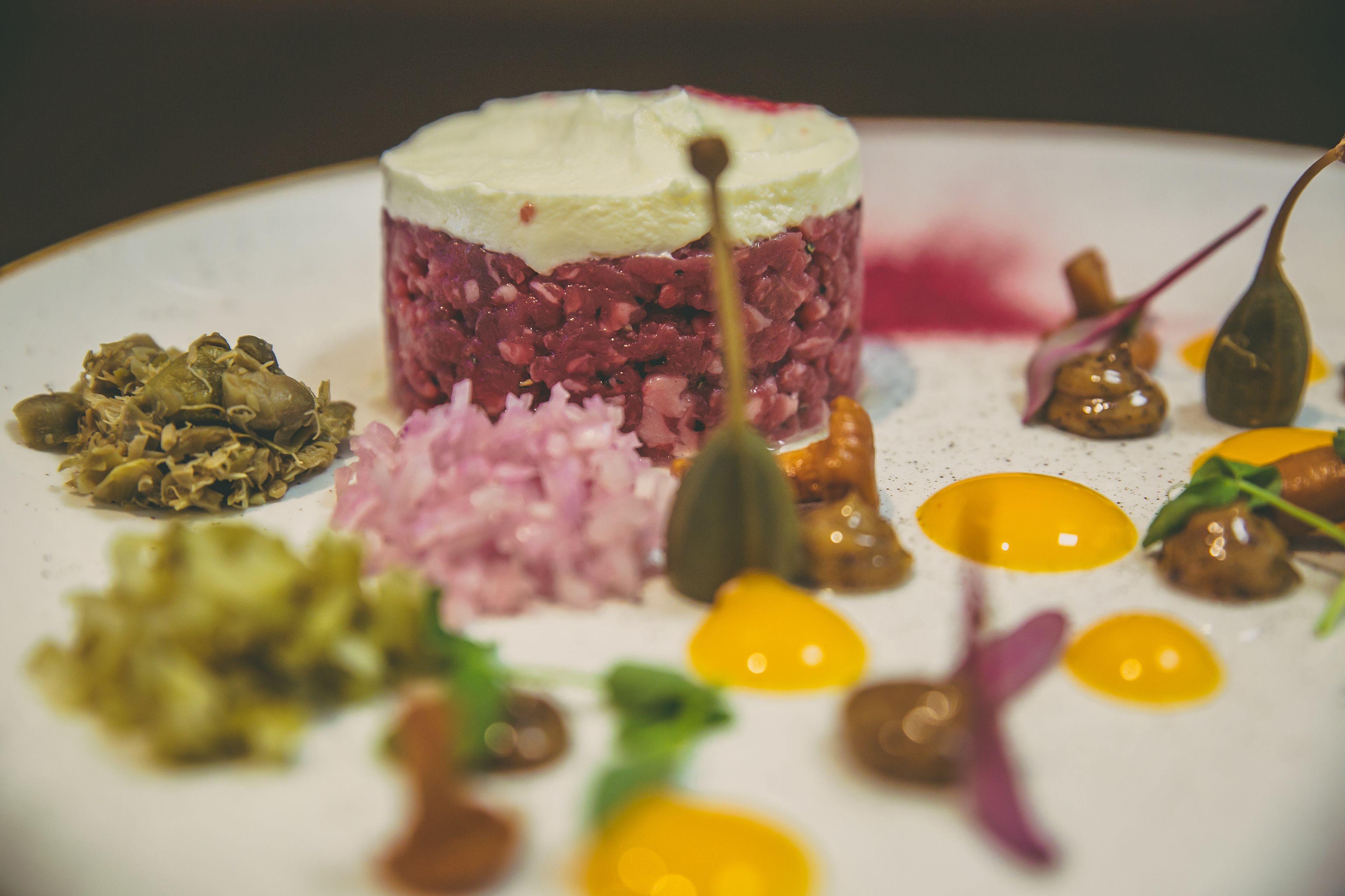 Un plato con una presentación en capas, adornado con diferentes verduras y salsas.