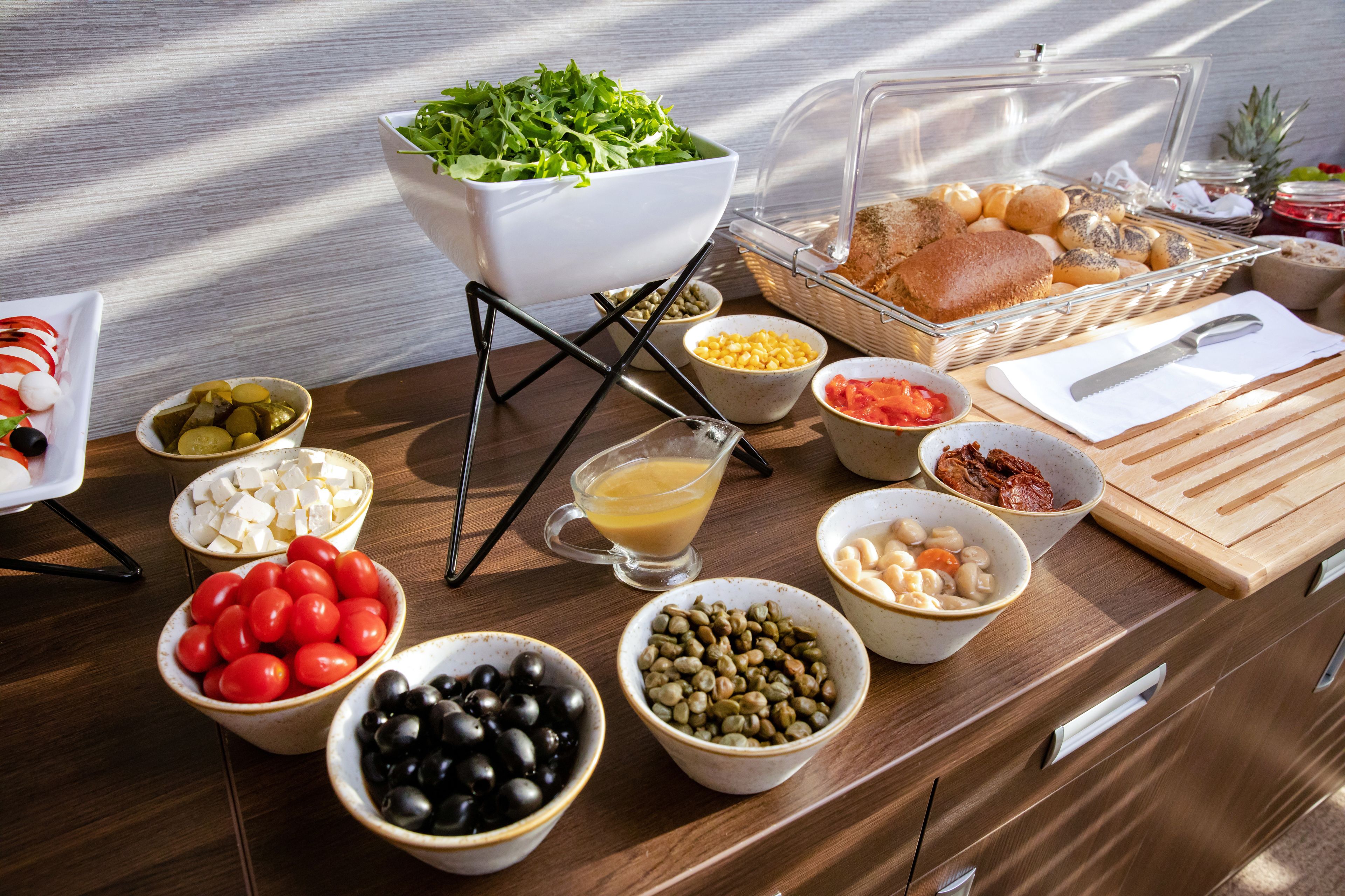 A buffet with various food items including tomatoes, olives, cheese, and bread.