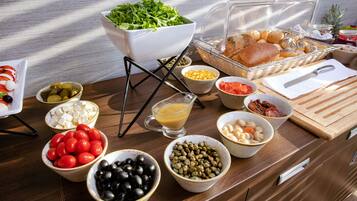A buffet with various food items including tomatoes, olives, cheese, and bread.