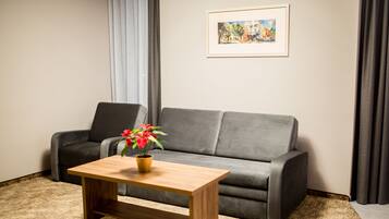 A living room with a grey sofa, a wooden coffee table with a potted plant, and a framed picture on the wall.
