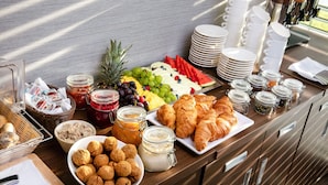 A breakfast buffet with various food items, including fruits, pastries, and condiments.