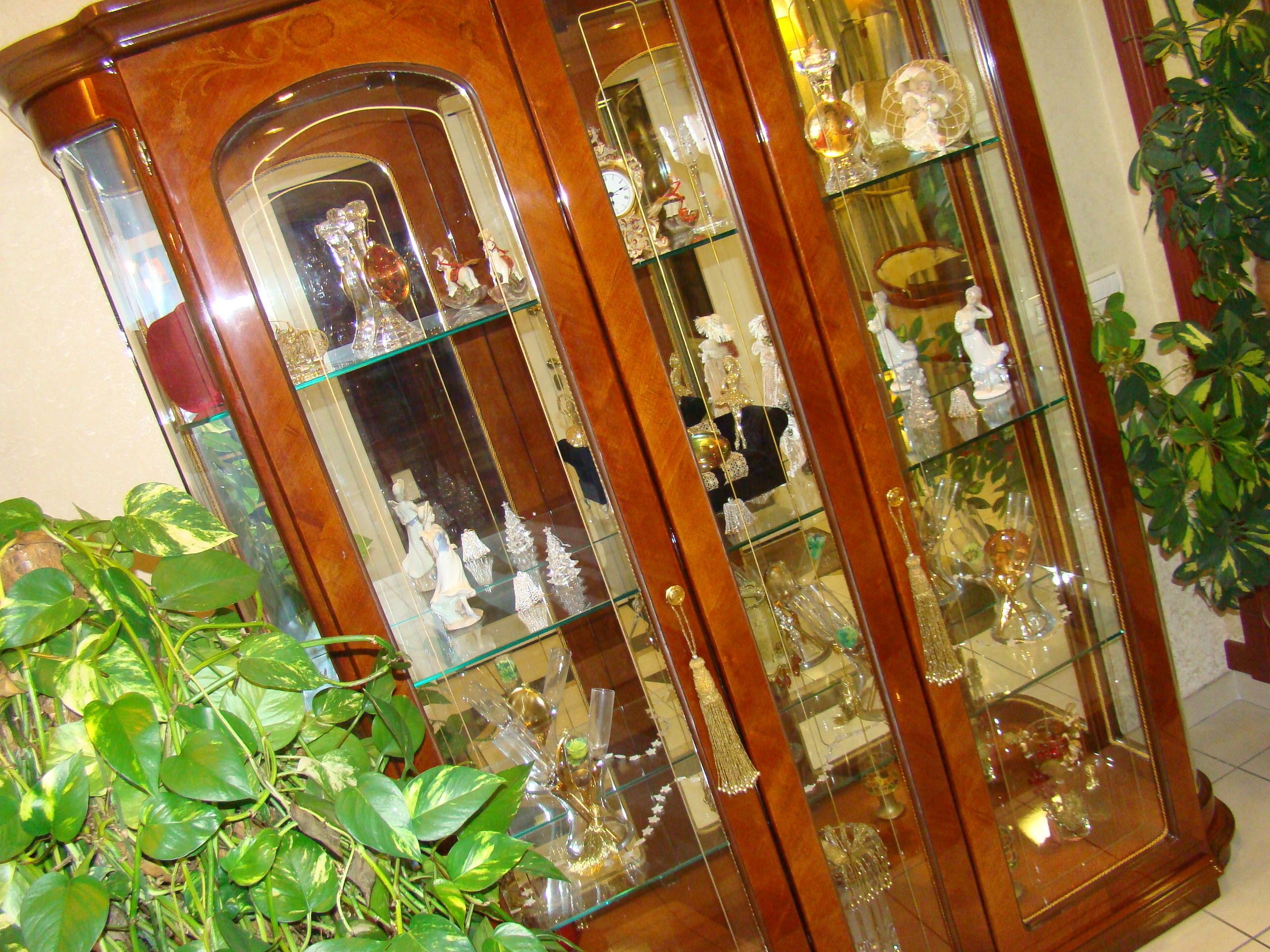 A wooden display cabinet with multiple glass shelves containing various decorative items.