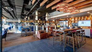 A modern bar area with high stools, a counter, and a large screen displaying content. - ibis Landshut City (Landshut)