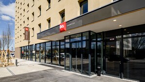Un hôtel moderne doté d’une façade en verre, d’une enseigne rouge et blanche bien visible et offrant une vue d égagée sur la rue.