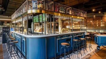 Zona de bar con taburetes, una barra y una vitrina de vidrio.