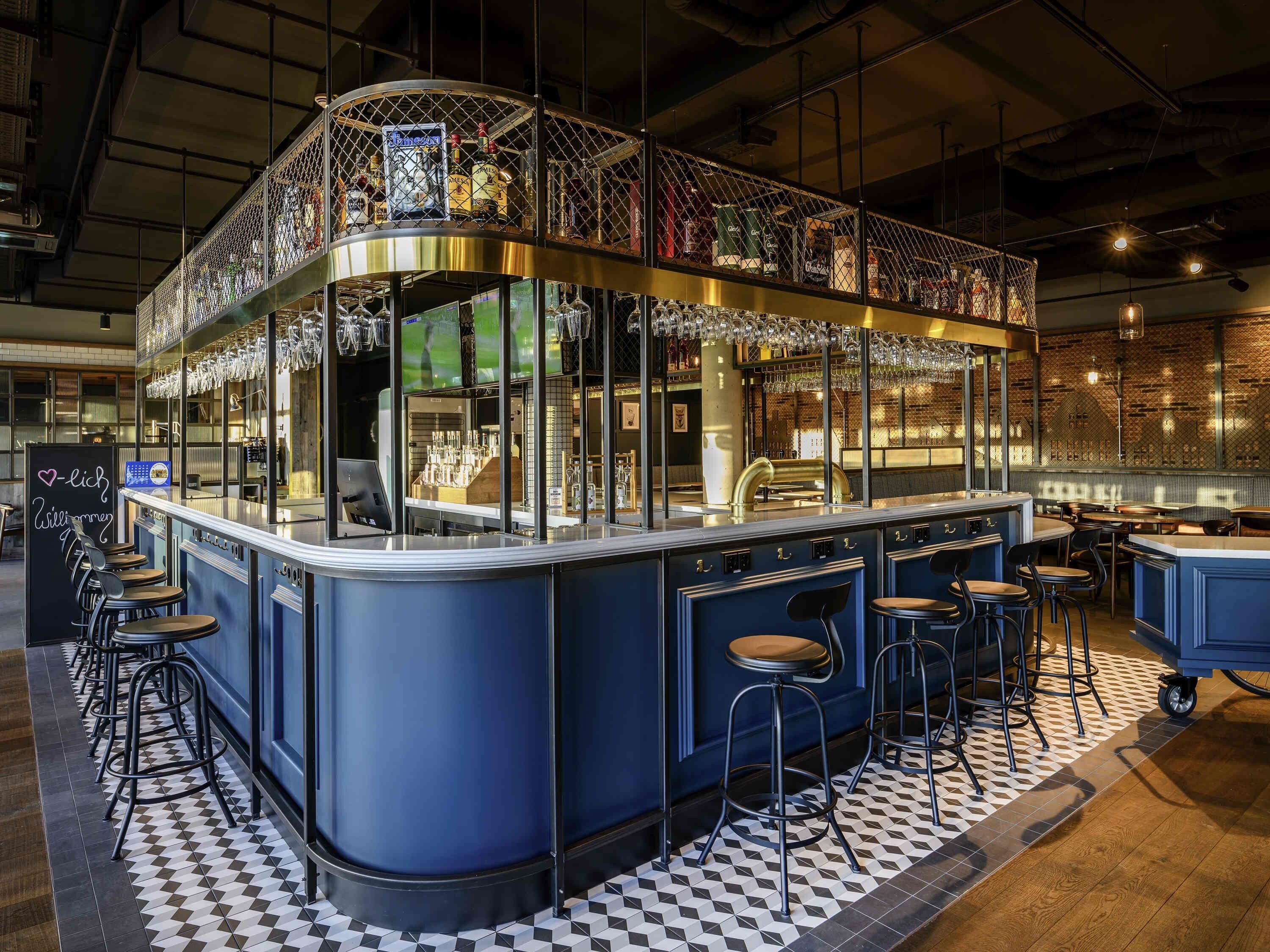 Zona de bar con taburetes, una barra y una exhibición de botellas.
