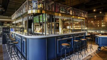 Zona de bar con taburetes, una barra y una exhibición de botellas.
