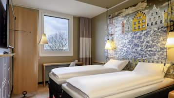 A hotel room with two beds, a window, a stone wall mural, and a TV.