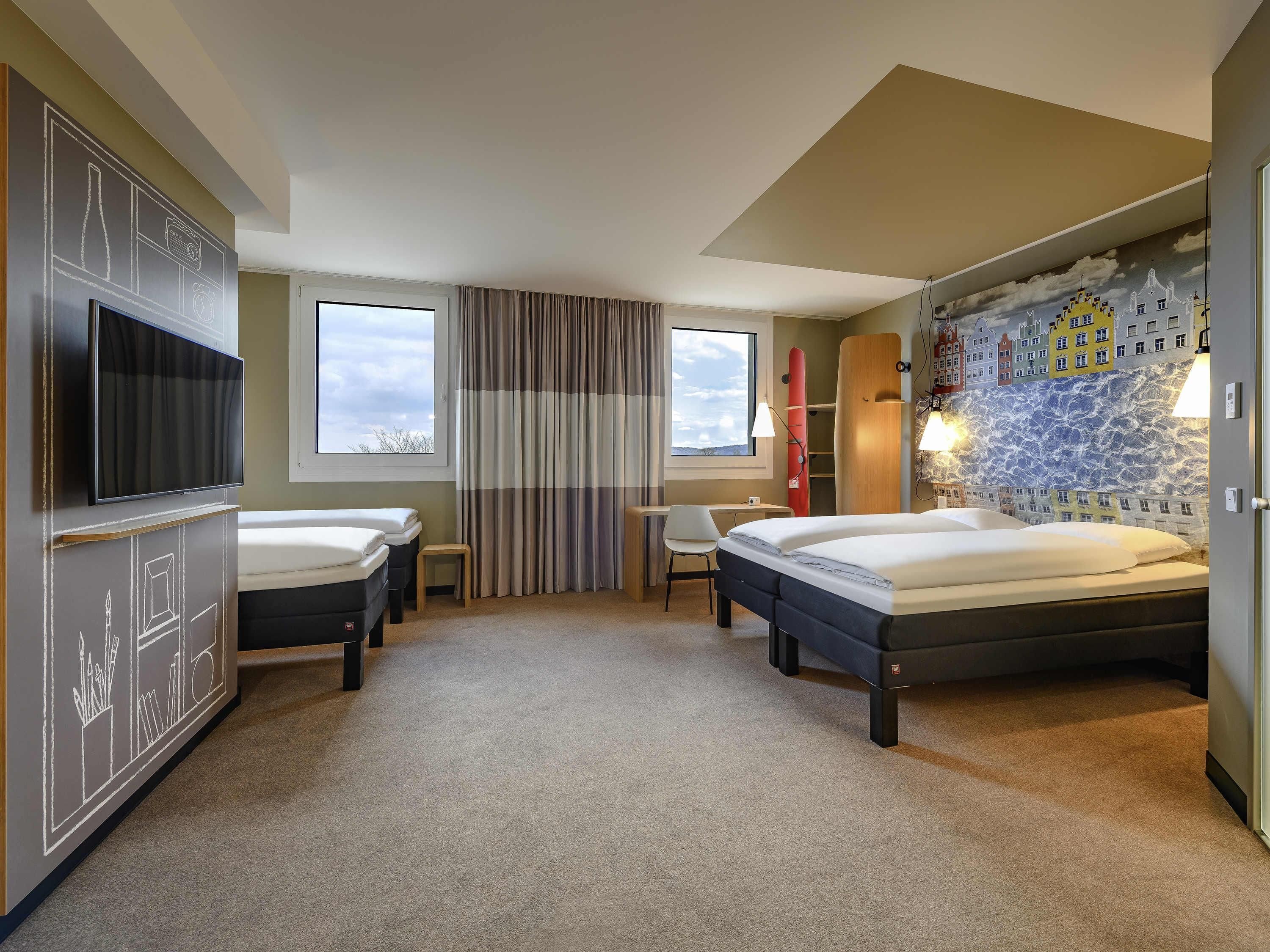 A hotel room with two beds, a TV, a desk, and a chair.
