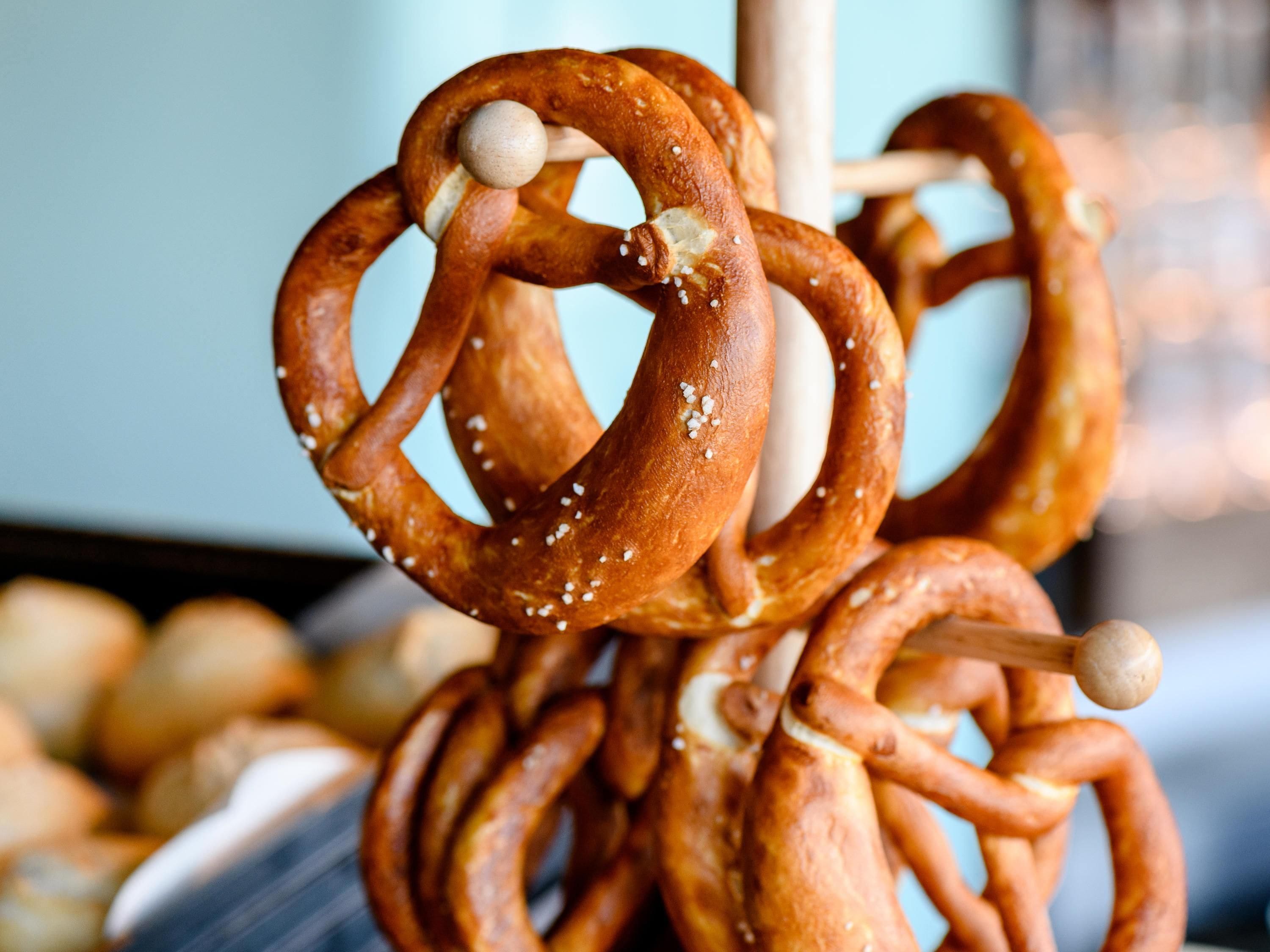 A rack of pretzels with visible salt crystals and a wooden stick.