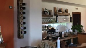 A kitchen with wine bottles on a wooden rack, a coffee machine, and various kitchen utensils. - Agriturismo Lo Scoiattolo (Montorio al Vomano)