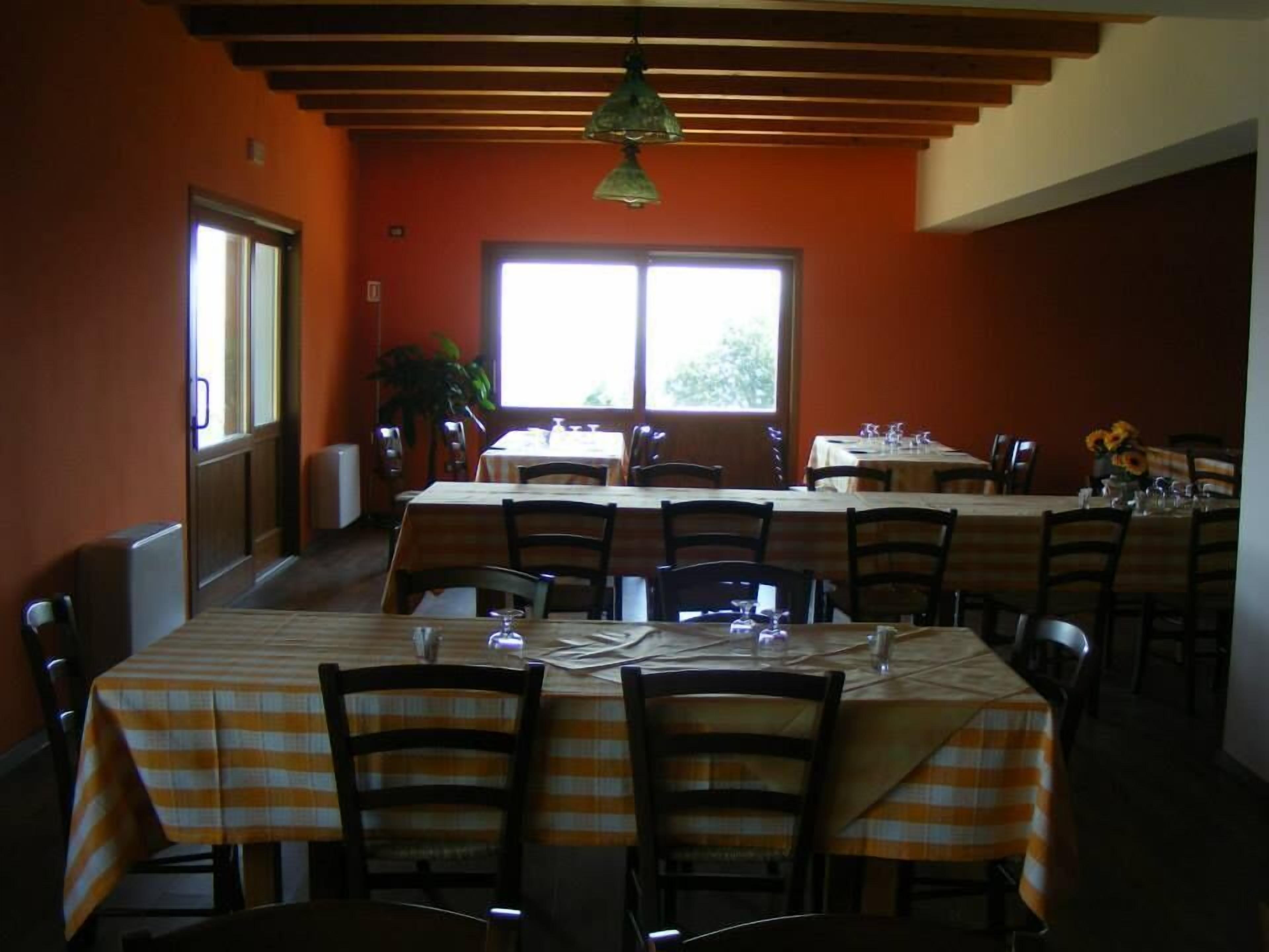 A dining area with tables set for service, chairs, and a large window providing natural light.
