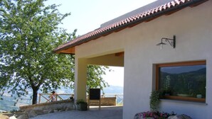 A modern house with a covered patio, a stone wall, and a view of the mountains. - Agriturismo Lo Scoiattolo (Montorio al Vomano)