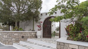 Un edificio de paredes de piedra con una puerta de madera y escalones que conducen a una puerta blanca.