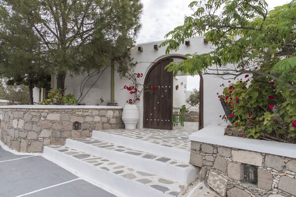 Un edificio de paredes de piedra con una puerta de madera y escalones que conducen a una puerta blanca.