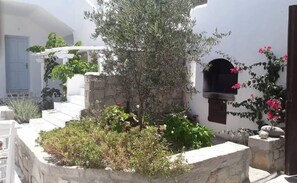 Un edificio tradicional blanco con una escalera de piedra que lleva a una puerta, rodeado de follaje y flores.