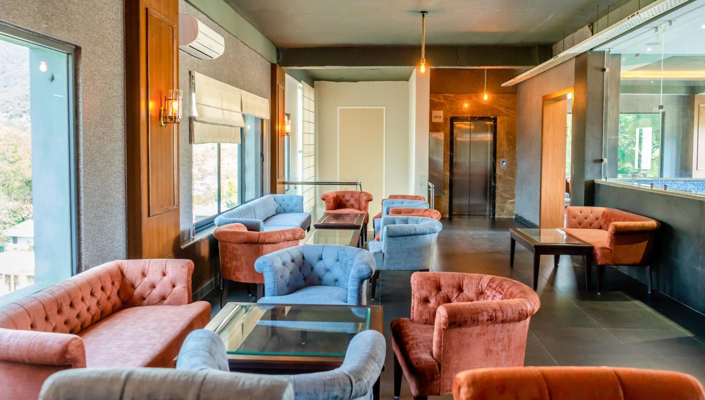 A modern lounge area with plush seating, a glass coffee table, and large windows offering views.