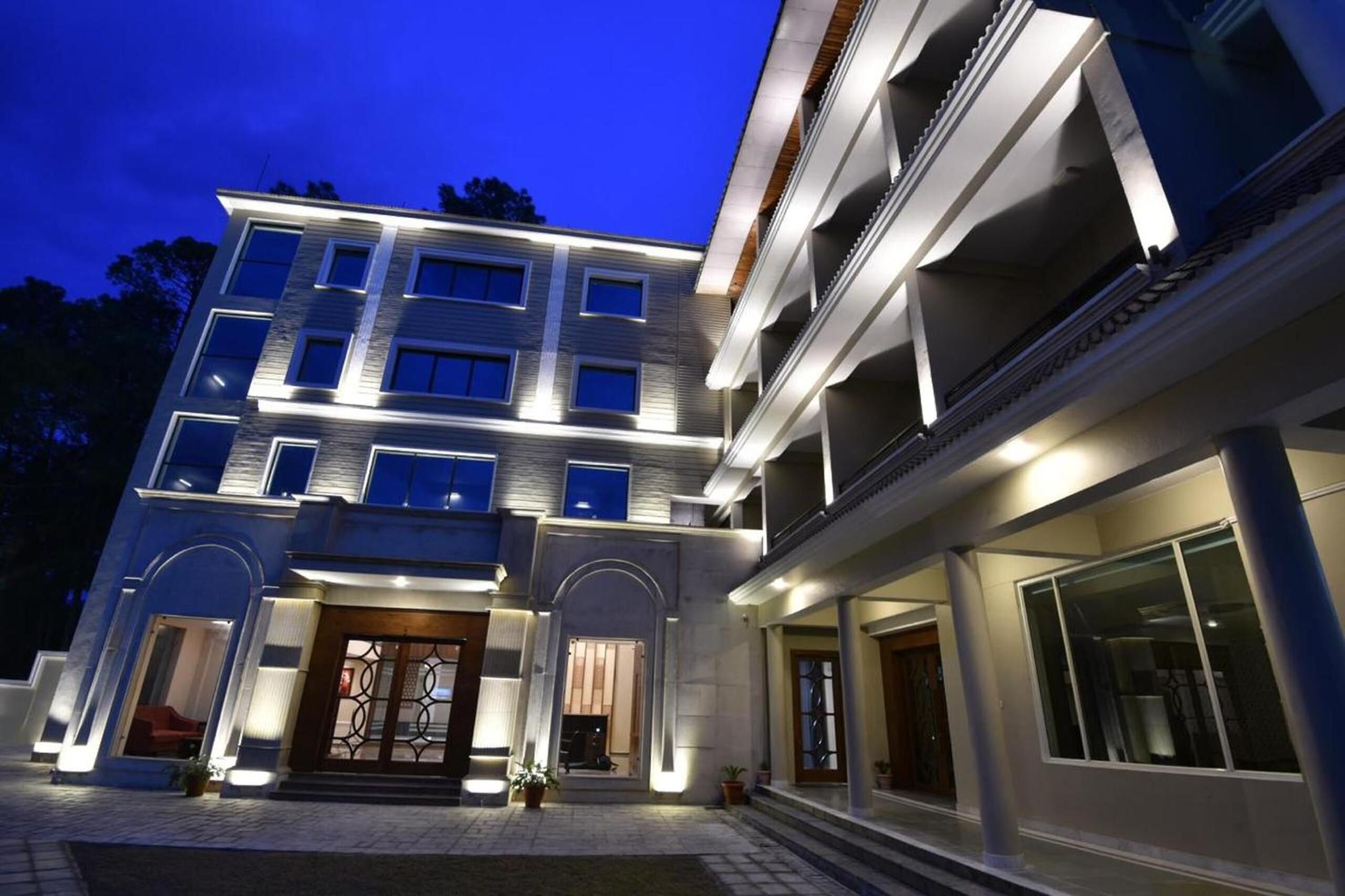 Un hotel de varios pisos con fachada moderna, grandes ventanales y una entrada bien iluminada.