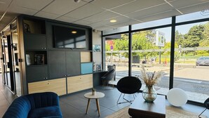 Un intérieur moderne avec un canapé, une petite table ronde et un téléviseur à écran plat fixé au mur.