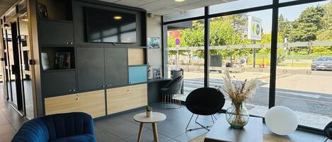 A modern interior with a sofa, a small round table, and a flat-screen TV mounted on the wall.