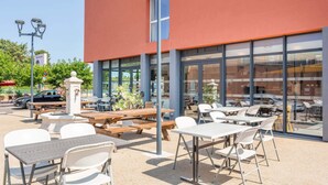 Un espace extérieur aménagé en terrasse, avec des tables et des chaises, un banc en bois et un lampadaire.