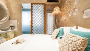 A modern hotel room with a large bed, a bathroom with a sink and mirror, and a decorative wall. - AmazeU Naxos (Naxos)