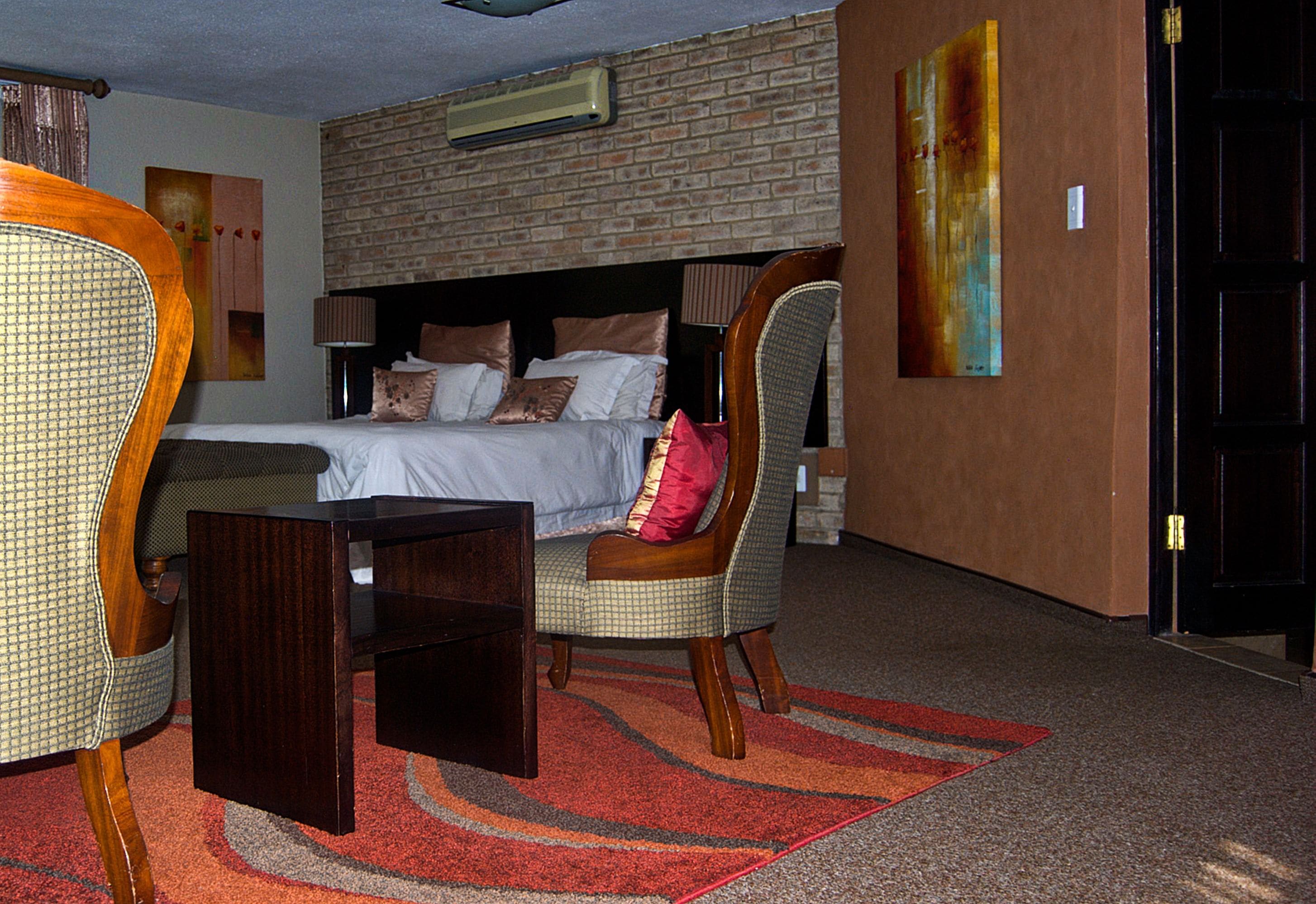 Une chambre d’hôtel avec un mur en briques, un lit avec des oreillers, une chaise, une petite table et un tapis.