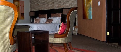 Une chambre d’hôtel avec un mur en briques, un lit avec des oreillers, une chaise, une petite table et un tapis.