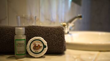 A bathroom with a white sink, a brown towel, and a bottle of conditioner shampoo.