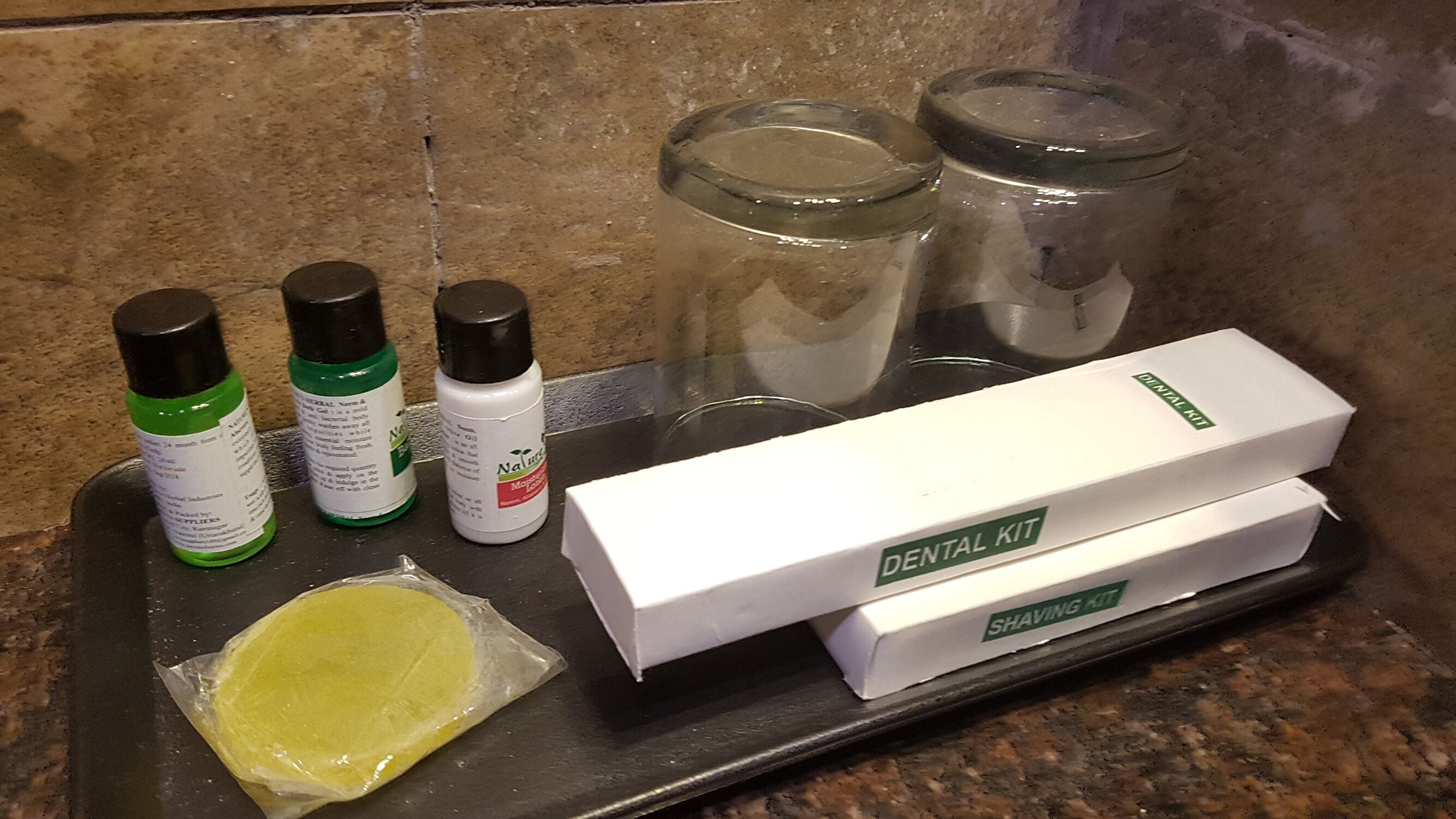 A countertop with a dental kit, shaving kit, and personal care products.