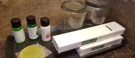 A countertop with a dental kit, shaving kit, and personal care products.