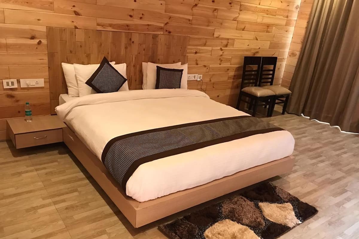 Un dormitorio con paneles de madera, una cama, almohadas, una mesita de noche y una silla.