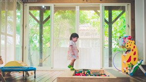 A child playing with toys in a room with large windows and a wooden floor. - Star&Moon Homestay (Ji'an)
