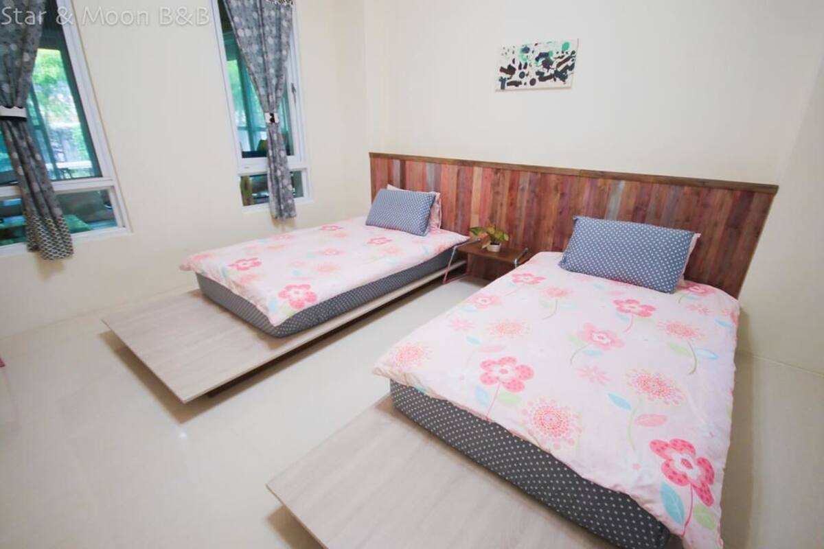 Un dormitorio con dos camas individuales, cabeceros de madera y una mesita de noche pequeña con una lámpara.