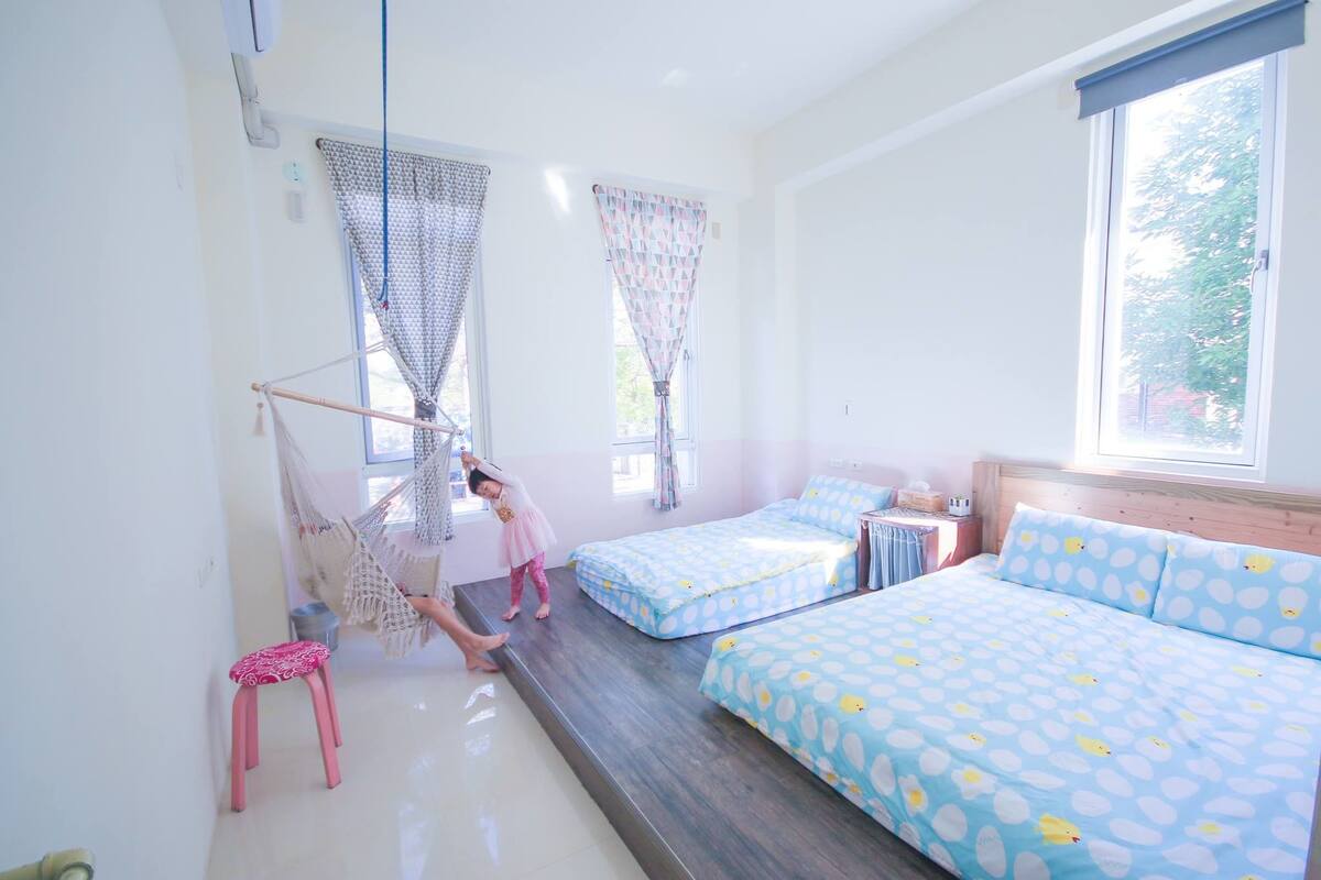 Un dormitorio con dos camas, un taburete pequeño y una hamaca.