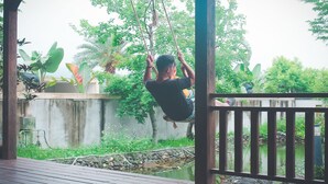 A wooden deck with a swing set and a pond in the background. - Star&Moon Homestay (Ji'an)