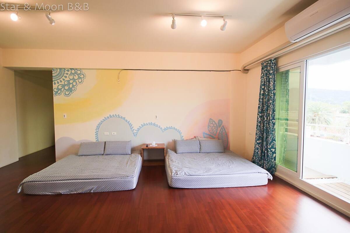 Una habitación con dos camas, una mesita pequeña y un ventanal con vistas.