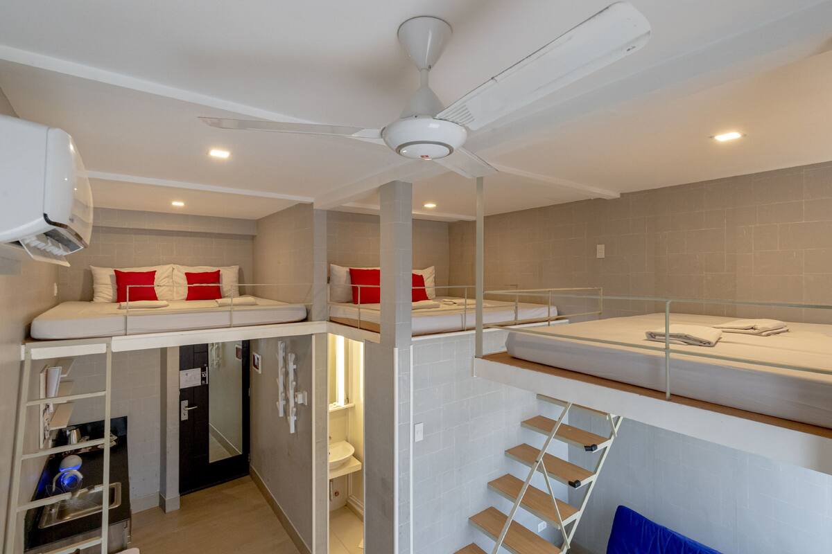A modern, compact room with bunk beds, a ceiling fan, and a small bathroom.