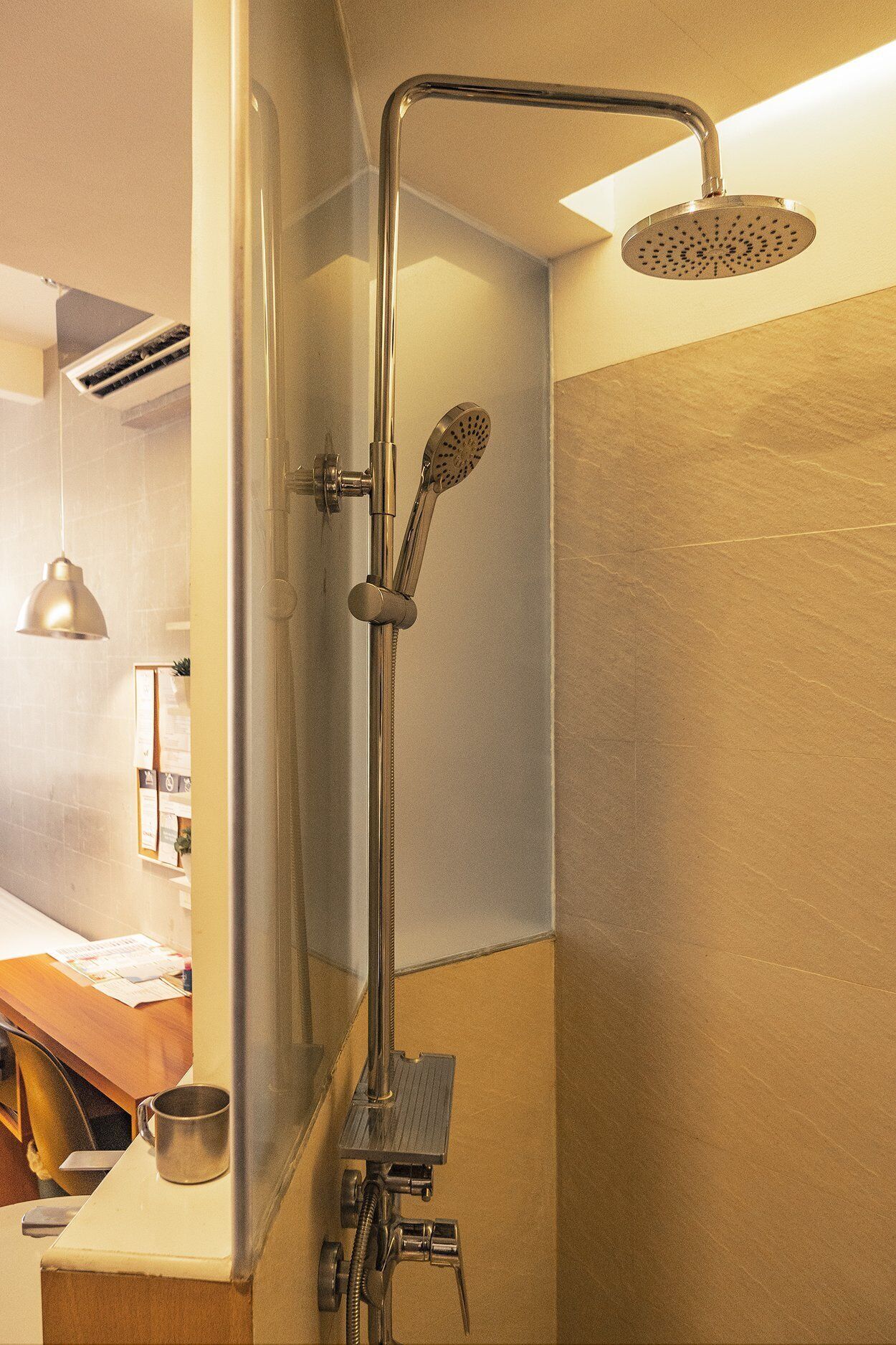 A modern shower with a handheld showerhead and a rain shower head, mounted on a wall with a towel rack below.