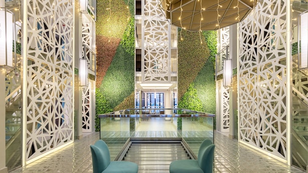 A modern lobby with a glass railing, green vertical gardens, and geometric white partitions. - Selah Pods Hotel Manila (Pasay)