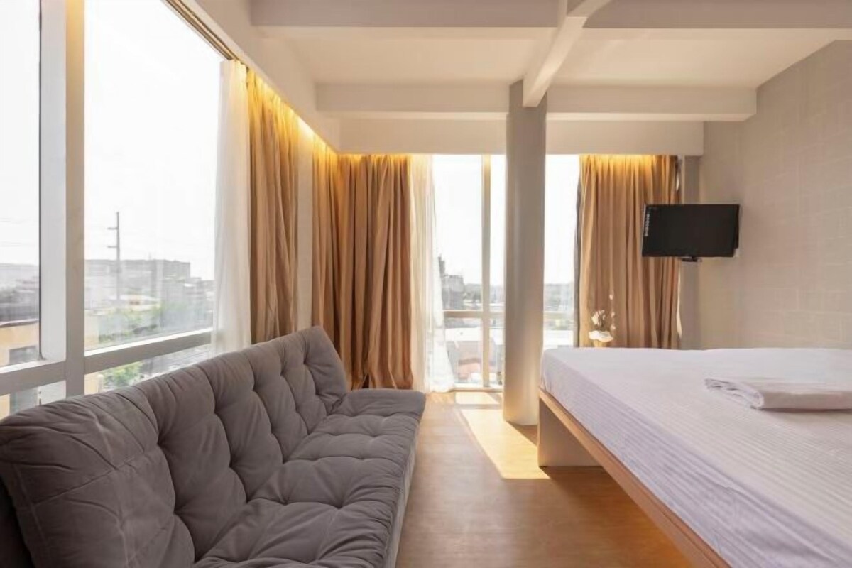 Ett modernt hotellrum med ett stort fönster, en soffa, en säng och en tv med platt skärm.