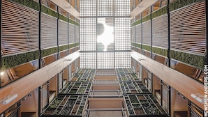 A modern interior with a central atrium, wooden slats, and green planters. - Selah Pods Hotel Manila (Pasay)