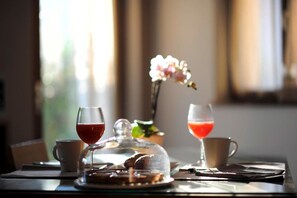 A table with a glass of red wine, a glass of rosé, a coffee cup, and a dessert under a glass dome. - Arcovacanze (Arco)
