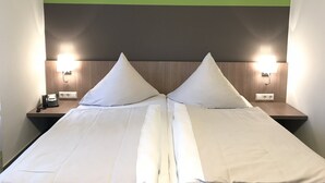 Un lit double avec deux oreillers, une tête de lit en bois et deux lampes de chevet.