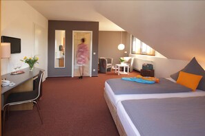 A hotel room with a bed, desk, chair, and a small seating area with a table and chairs. - Astra Hotel Garni (Rastatt)