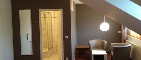 Una habitación moderna con ducha, una mesita y dos sillas.