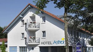 Un bâtiment blanc doté d’un balcon et d’une enseigne sur laquelle on peut lire « HÔTEL Astra ».