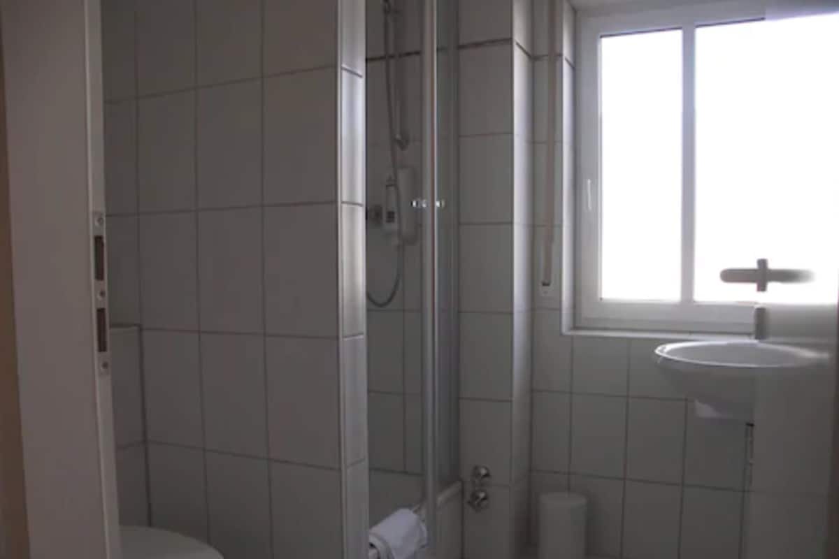 A bathroom with a toilet, a shower, and a sink.