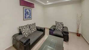 Una sala de estar moderna con dos sofás, una mesita de centro de vidrio y una planta en maceta.
