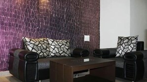 Un salon moderne avec un mur à texture, un canapé d’angle agrémenté de coussins à motifs et une table basse.